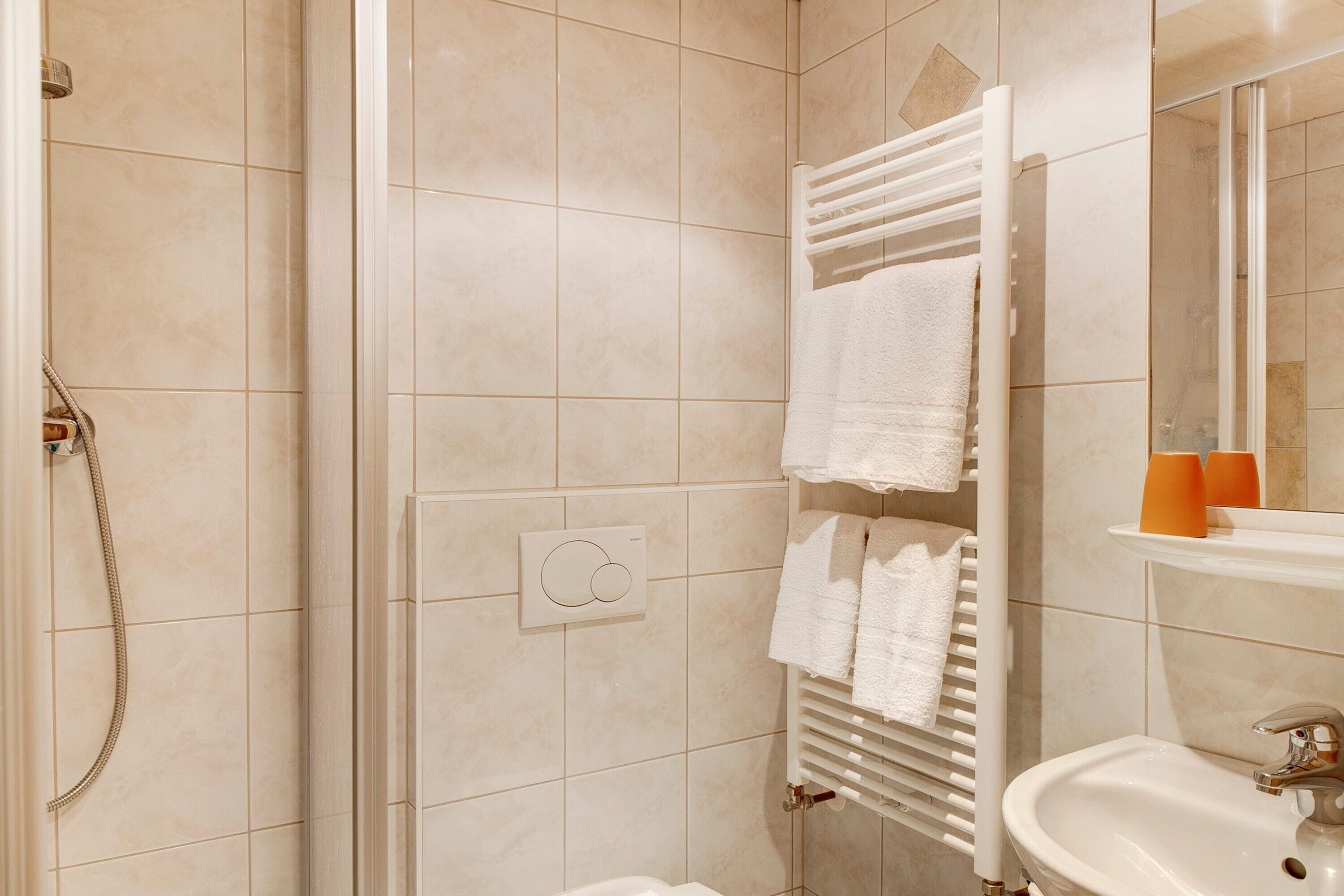 A bathroom with a shower, a sink, and a towel rack.