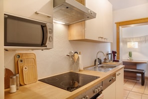A modern kitchen with a microwave, stove, and wooden cutting board.