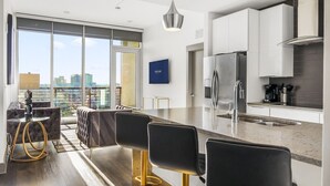 Une cuisine moderne dotée d’un grand îlot central, d’appareils électroménagers en acier inoxydable et offrant une vue sur la ville.