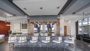 Un espace bar moderne doté d’un îlot central, de tabourets de bar et de luminaires suspendus.