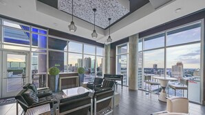Un salon spacieux offrant une vue sur la ville, doté de grandes fenêtres et d’un mobilier moderne.