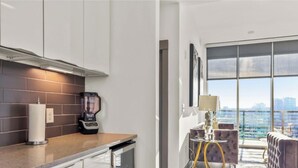 Une cuisine moderne dotée d’une machine à café intégrée et offrant une vue sur le paysage urbain grâce à de grandes fenêtres.