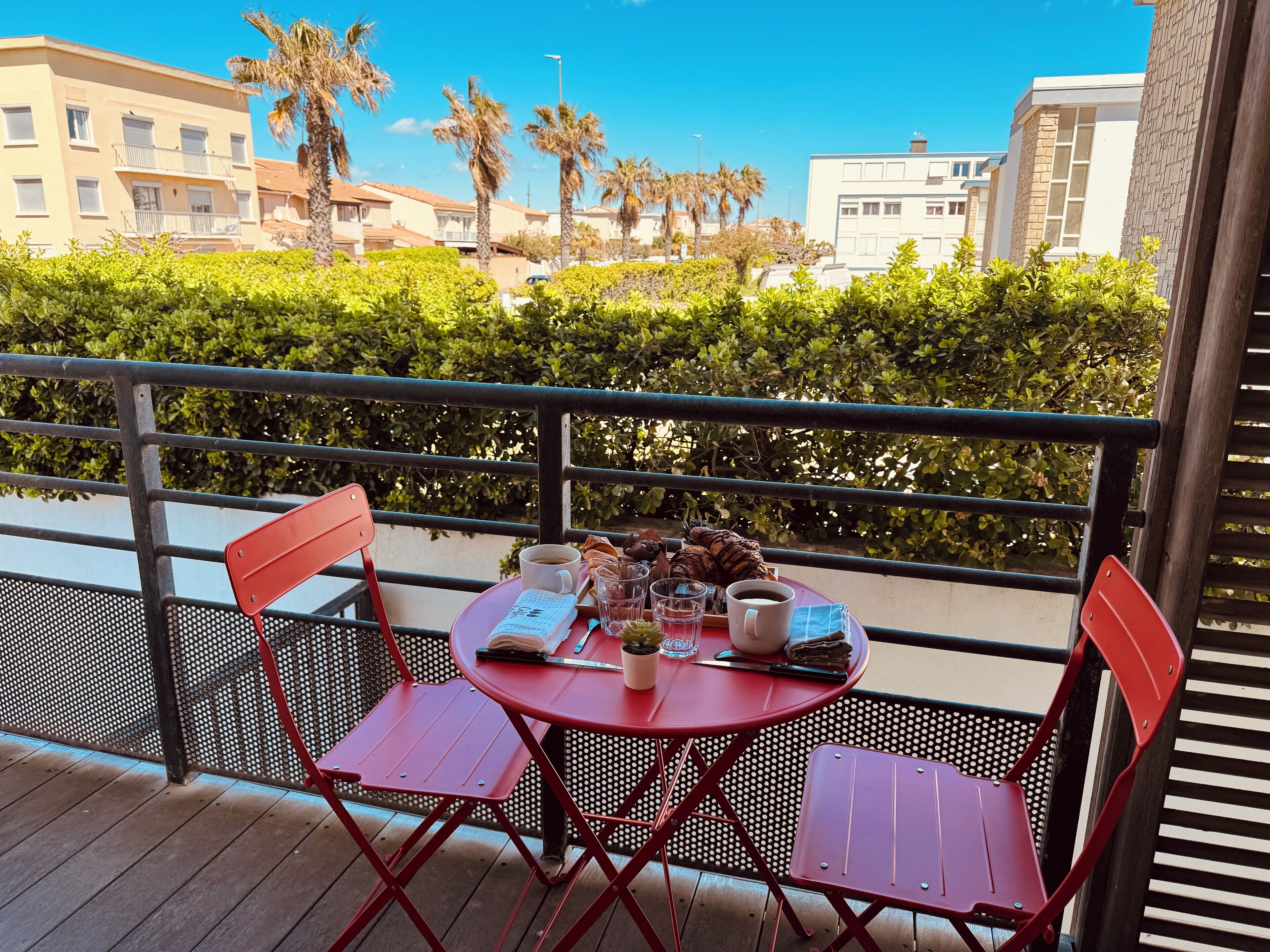 Ein Balkon mit einem Tisch für zwei Personen, ausgestattet mit einer Kaffeetasse, einem Buch und einem Glas Wasser.