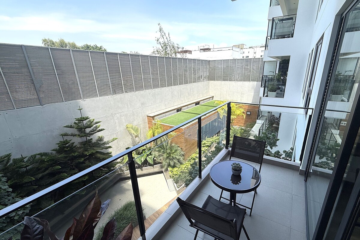A balcony with a glass railing, a small table, and two chairs.