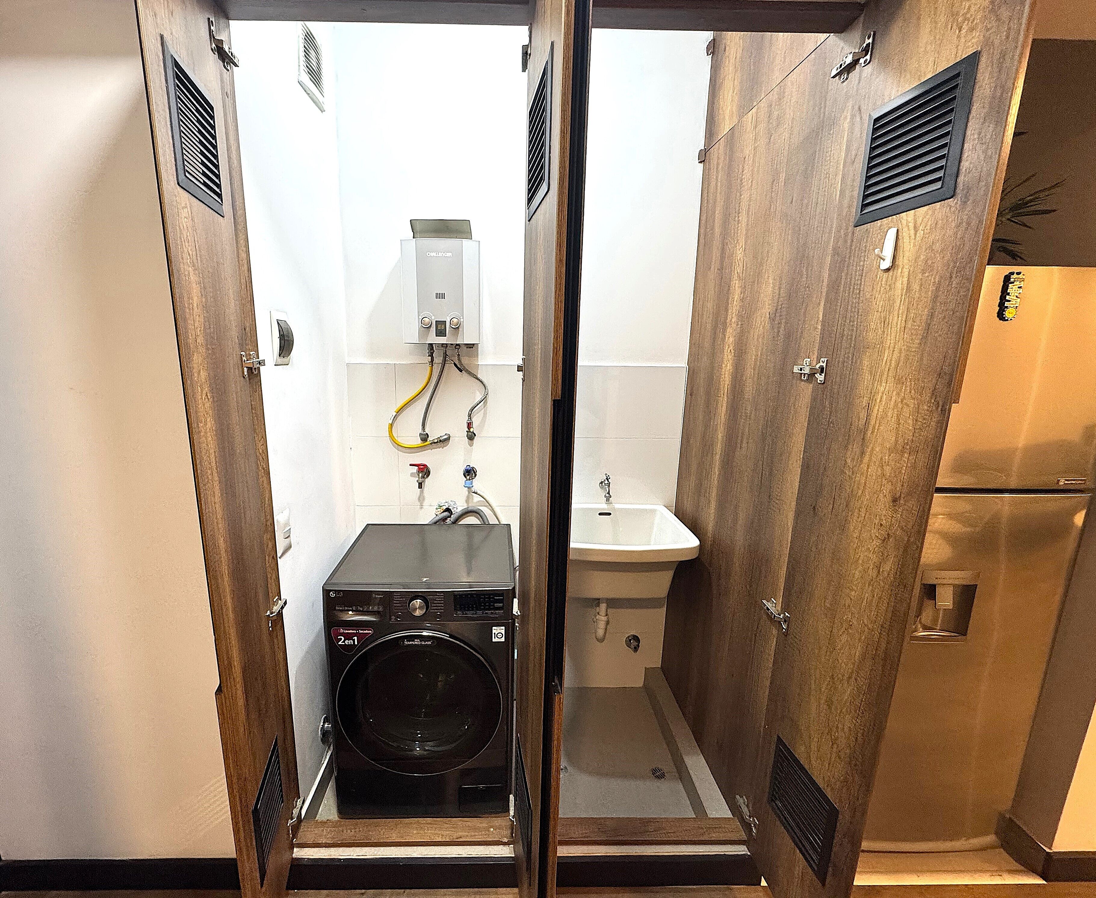 A compact bathroom with a washing machine, a sink, and a toilet.