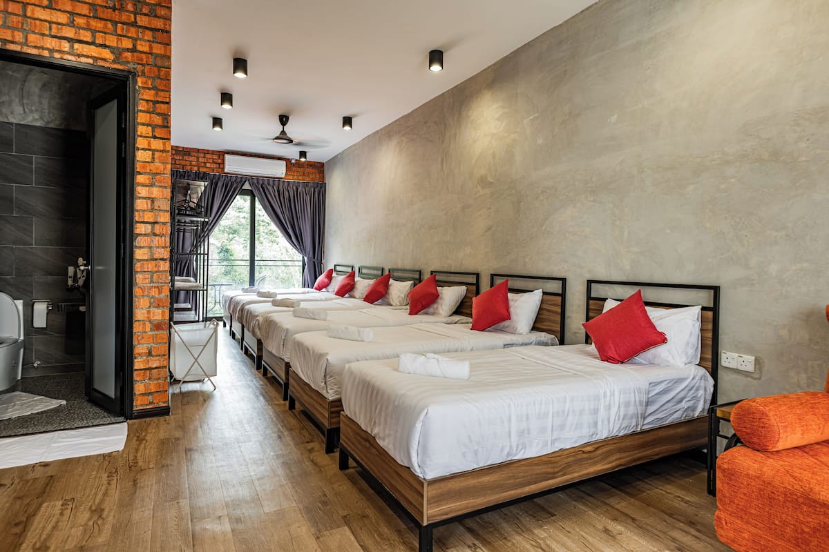 Una habitación de hotel con cuatro camas, una pared de ladrillo y un ventanal grande.