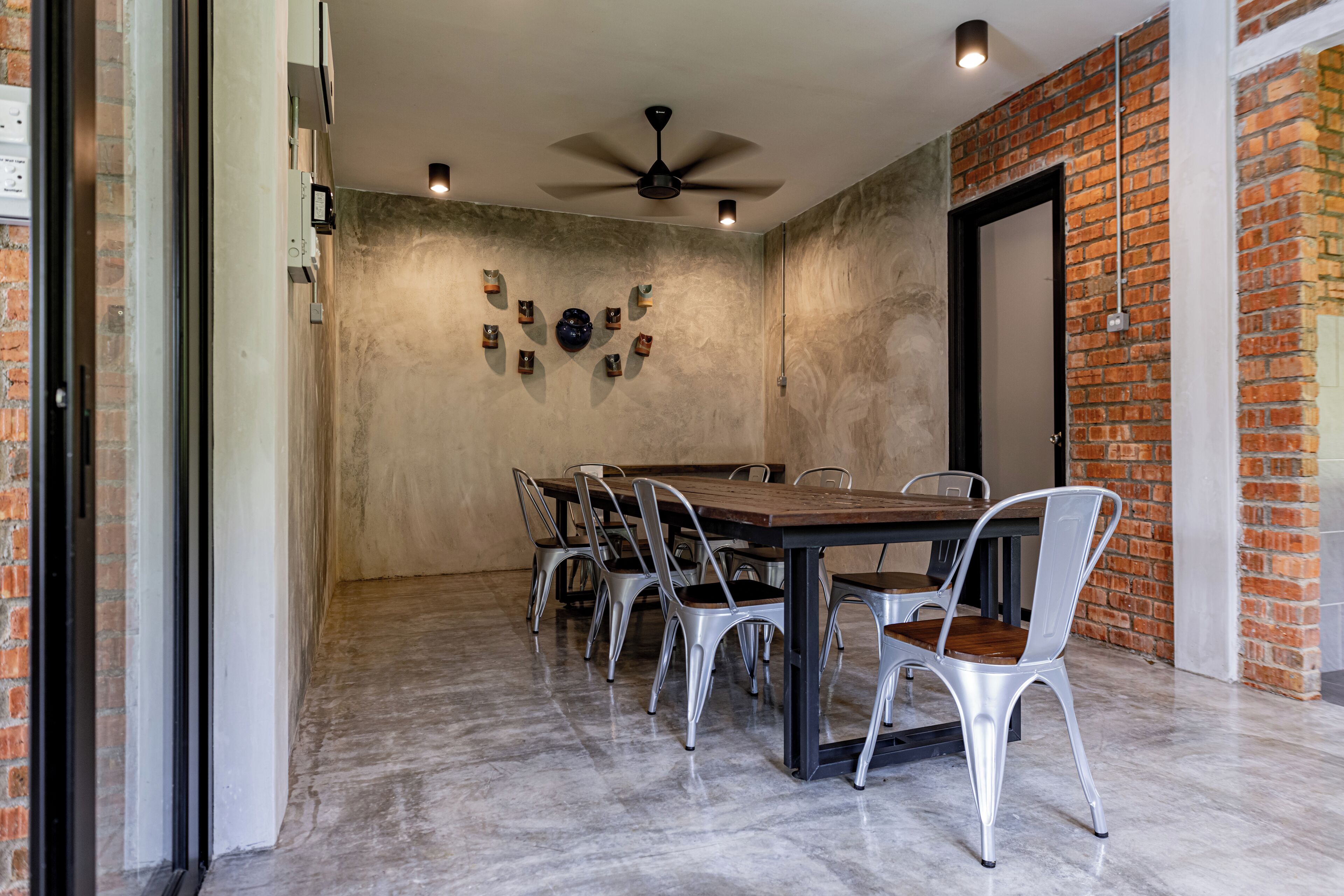 Un coin repas avec un mur en briques, un ventilateur de plafond et une table avec des chaises.