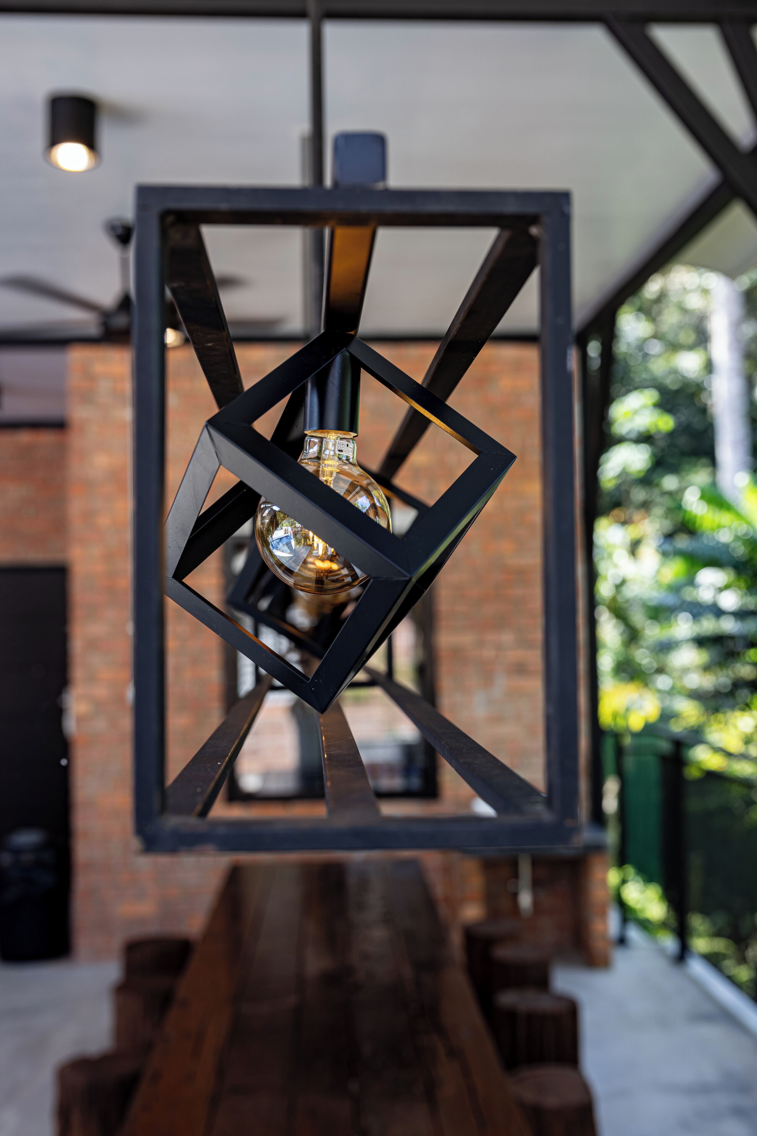 A modern interior with a geometric metal light fixture and a wooden bench.