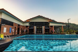 A swimming pool with a checkered pattern, a brick building with a covered entrance, and lifebuoys on the wall.
