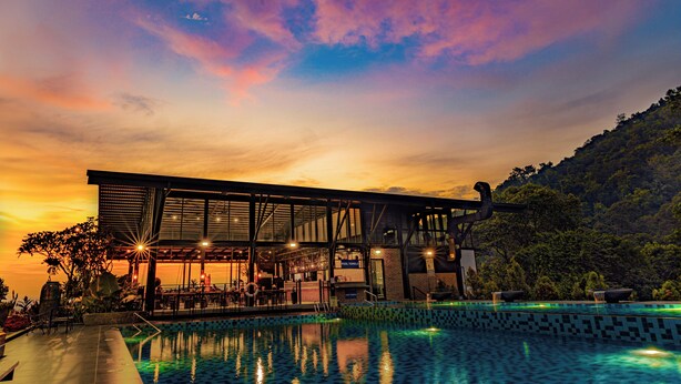 A modern building with a pool, surrounded by lush greenery and a sunset sky. - Sebayu Retreat Gopeng (Ipoh)