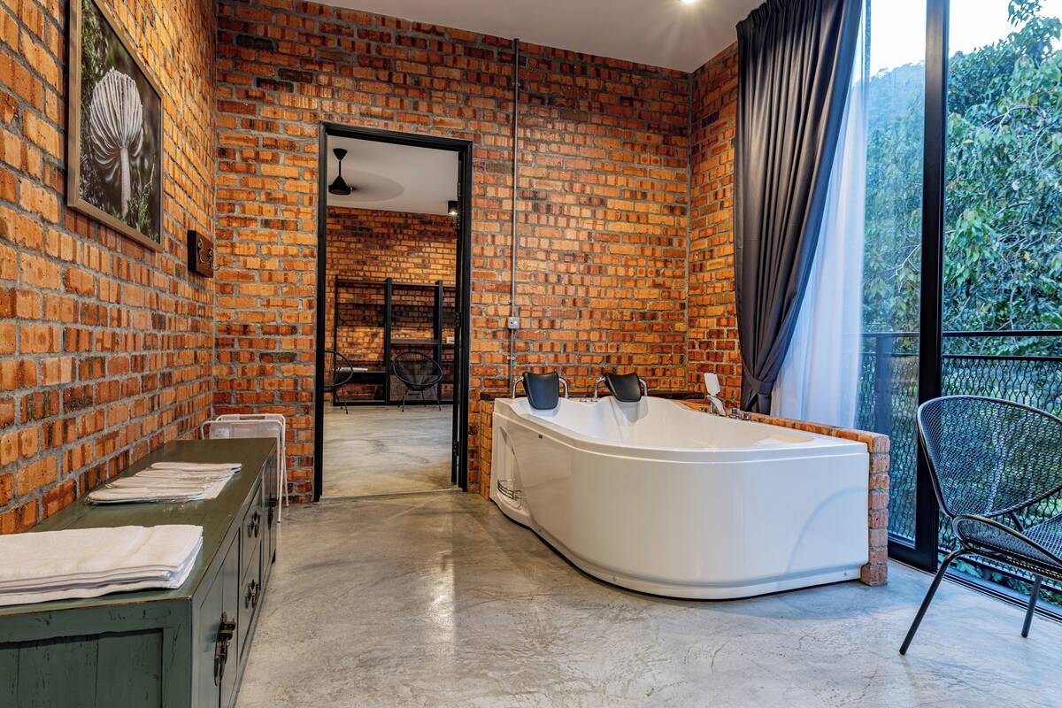 Un baño moderno con una bañera grande, un armario verde y vistas a un balcón con una silla.