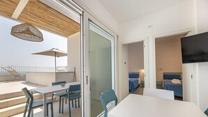 Una habitación de hotel moderna con balcón, comedor y televisor.