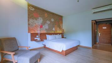 Une chambre d’hôtel avec un lit, une chaise, une fresque murale et une porte.