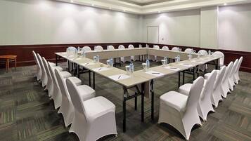 A conference room with a long table, white chairs, and water bottles.