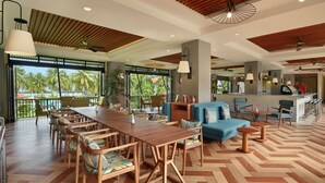 A spacious indoor area with a wooden dining table, chairs, a sofa, and a bar area. - Manado Tateli Resort and Convention (Pineleng)