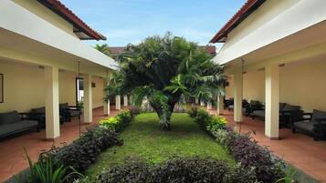 A courtyard with a central palm tree, surrounded by seating areas and a well-maintained garden.