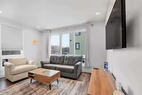 A modern living room with a sofa, a coffee table, and a TV mounted on the wall.