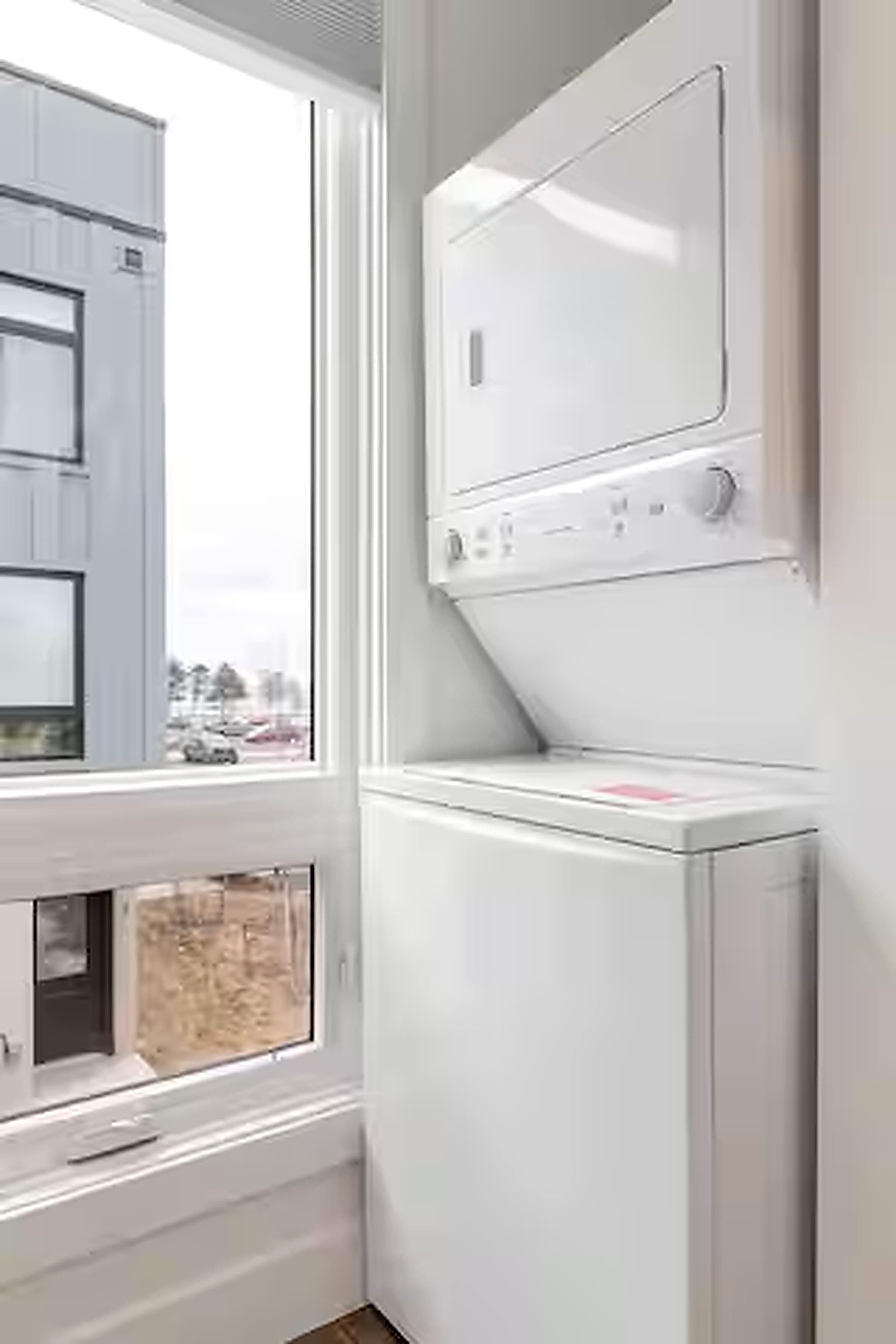Une buanderie équipée d’un lave-linge et d’un sèche-linge, avec une fenêtre et une porte.