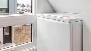 A laundry room with a washer and dryer, a window, and a door. - West Bay Hideaway | Rooftop Condo Near Beach/DT TC (Traverse City)