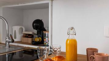 A kitchen counter with croissants, a glass of orange juice, and a coffee maker.