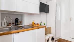 A modern kitchen with white cabinetry, a wooden countertop, a built-in sink, and a coffee maker.