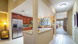 A spacious kitchen with a refrigerator, microwave, and granite countertops. - Country Club Experience (Palm Desert)