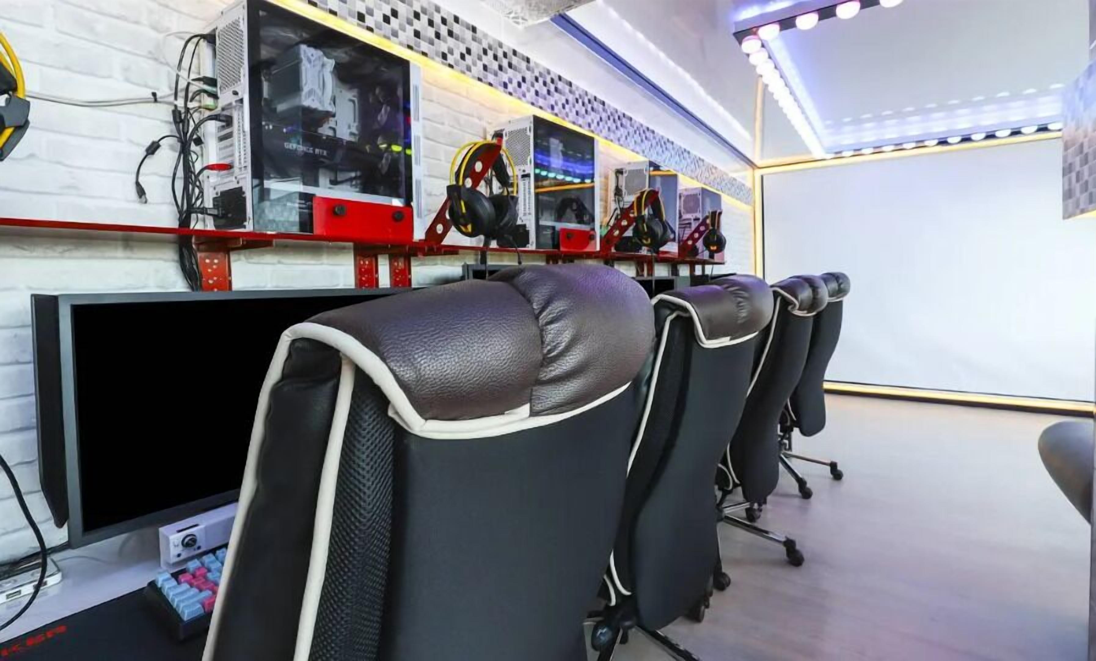 A gaming room with multiple monitors, gaming chairs, and a white brick wall.