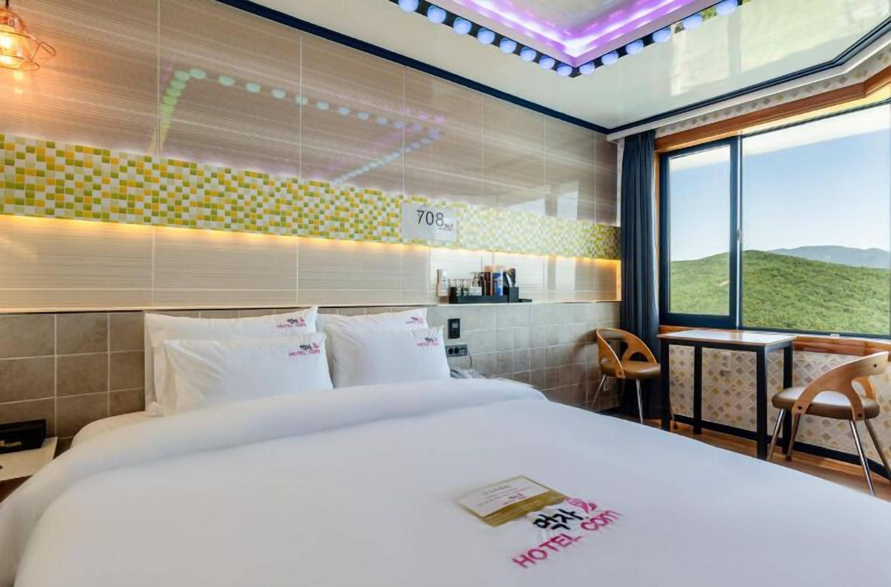 A hotel room with a bed, a desk, and a view of the hills.