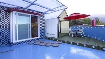 A covered outdoor area with a table and chairs, a red umbrella, and a white sign reading "Nature Carnival."