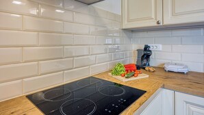 Een moderne keuken met witte metrotegels, een zwart inductiekookveld en houten aanrechtbladen.