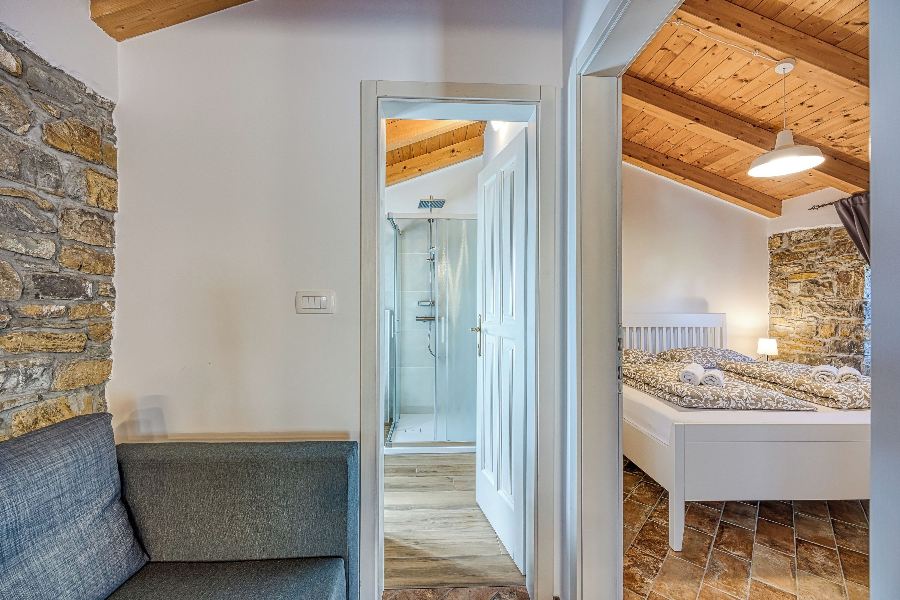Una camera da letto con parete in pietra, soffitto in legno e un letto con asciugamani.
