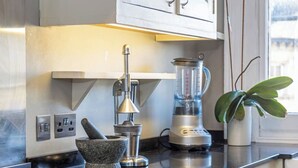 A kitchen with a gas stove, a blender, a mortar and pestle, and cabinets. - Spacious Central Hove Beach Flat (Hove)