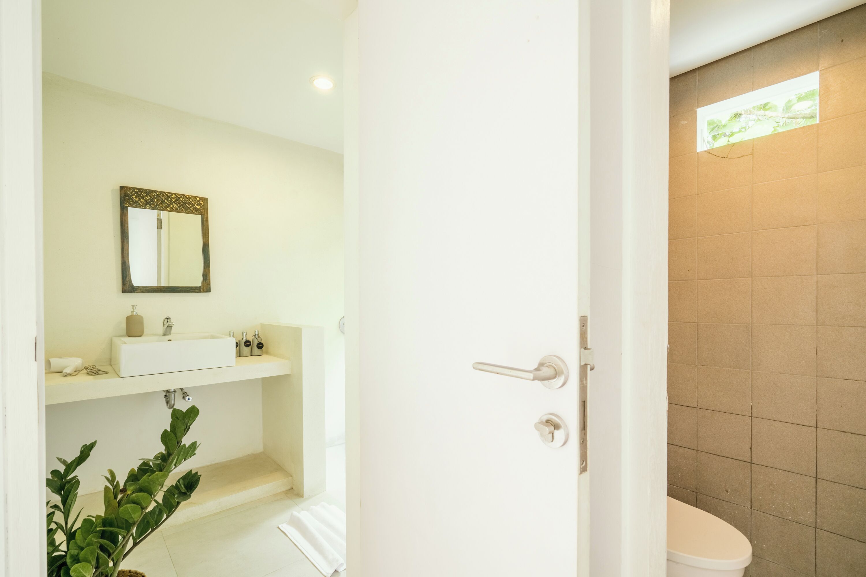 Un baño con lavamanos, espejo e inodoro blancos.