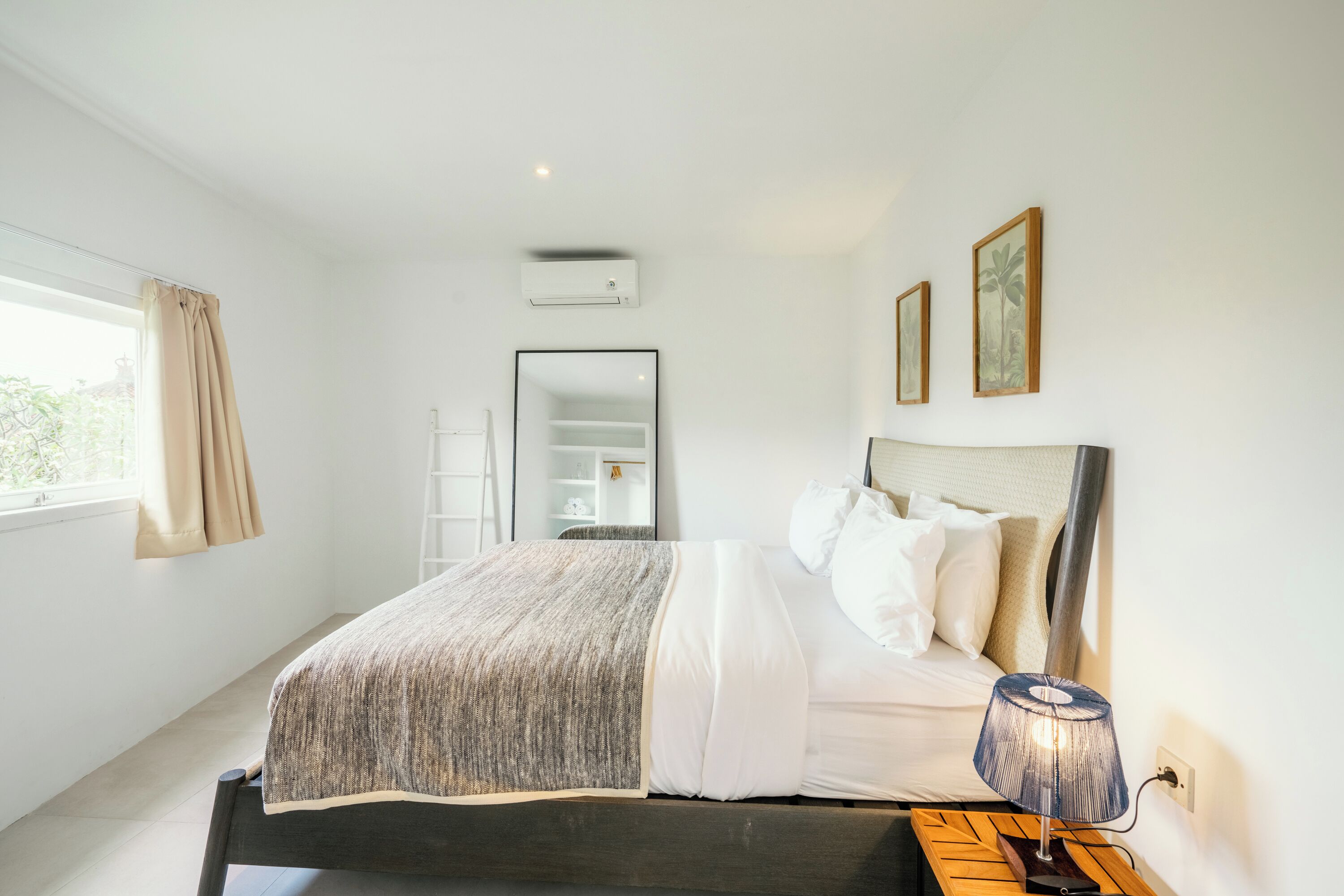 A bedroom with a bed, bedside lamp, and a window with curtains.