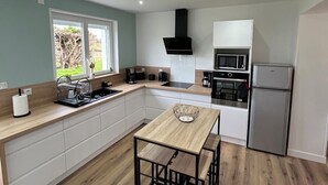 A modern kitchen with a central island, built-in appliances, and a view of the outdoors. - Agréable Maison au Calme , Proche de la mer (Meursac)