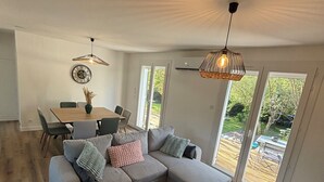A modern living room with a grey sectional sofa, a round coffee table, and a dining area with a table and chairs. - Agréable Maison au Calme , Proche de la mer (Meursac)