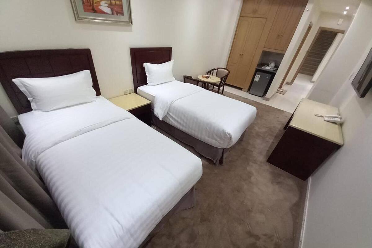 Een hotelkamer met twee enkele bedden, een kleine tafel, een stoel en een bureau met telefoon.