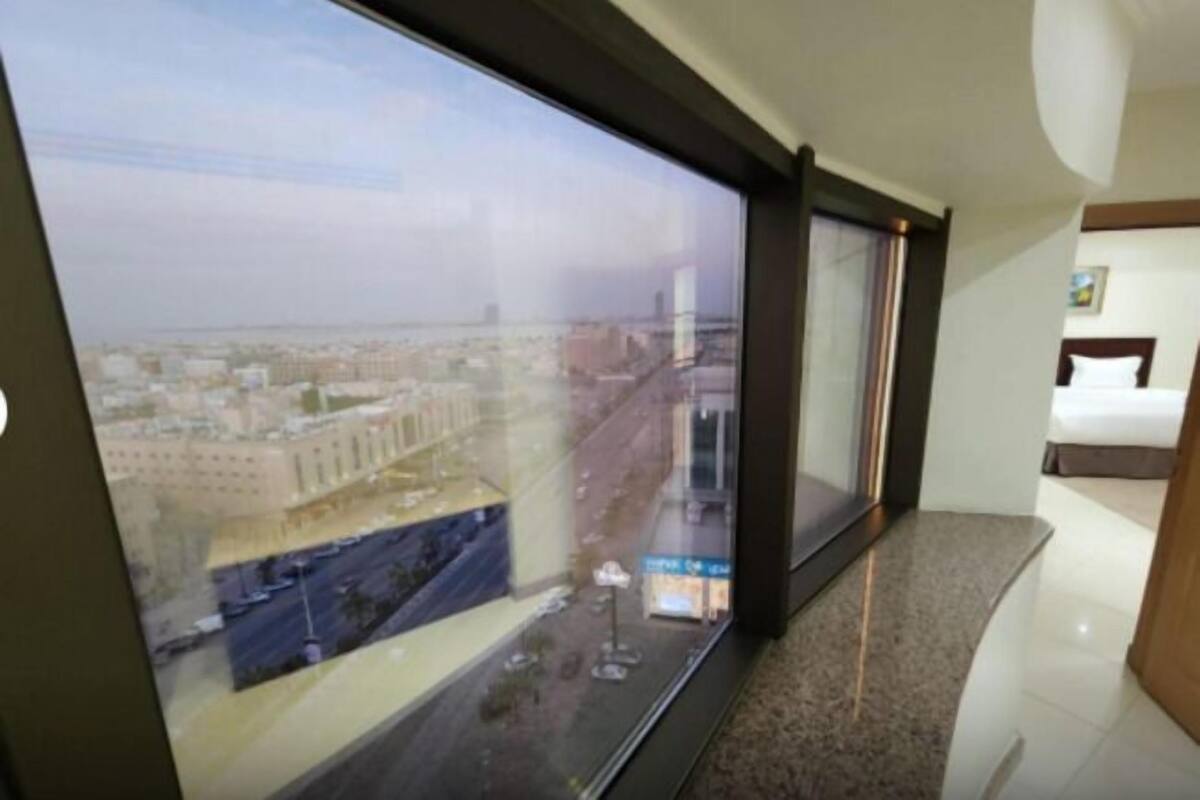 Hotelkamer met een groot raam met uitzicht op de stad, een bed en een klein tafeltje.