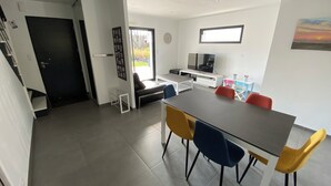 A modern living room with a dining area, a TV, and a window with a view. - Maison 4ch/8pers Bourg de Baden, Proche des Plages au Coeur du Golfe du Morbihan (Baden)