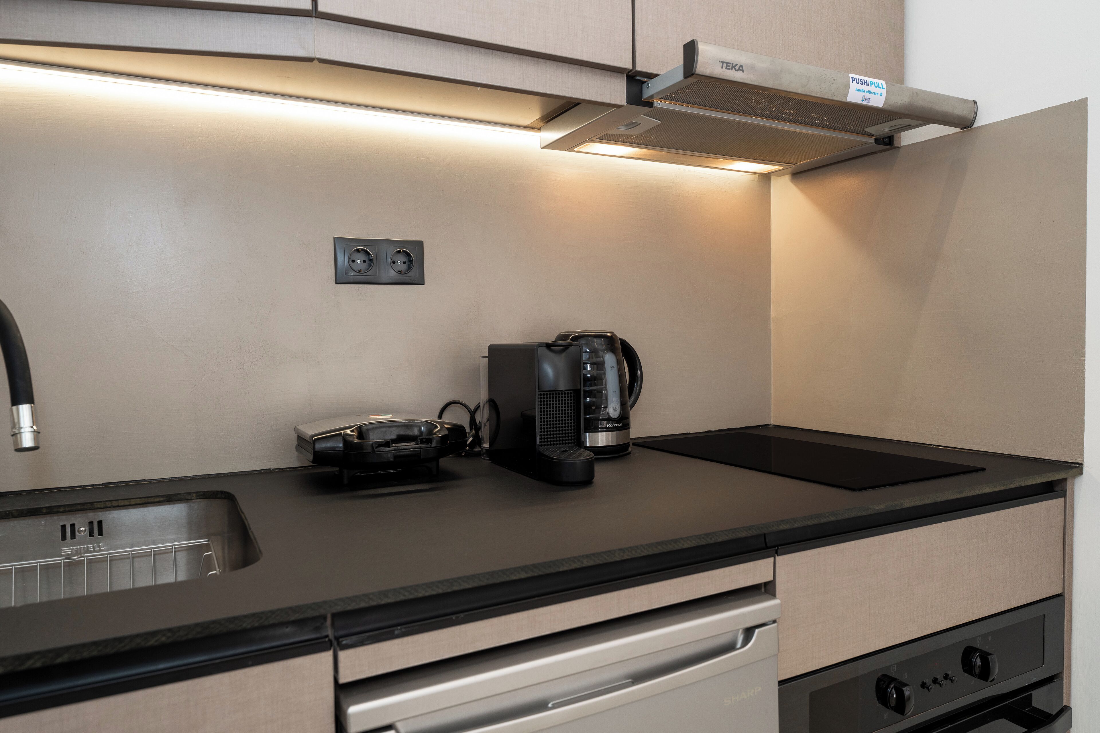 A modern kitchen with a built-in stove, a coffee maker, and a sink.