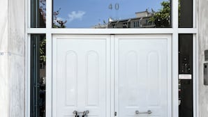 A double white door with a small window above it, a number "40" reflected in the window, and a doormat on the ground. - Minimal Studio with Balcony in Central Athens  (Athens)