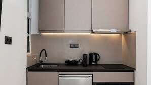 A compact kitchen with a dishwasher, oven, and a coffee maker on the countertop. - Minimal Studio with Balcony in Central Athens  (Athens)