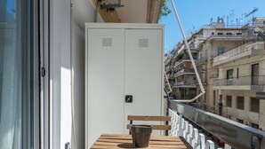 A balcony with a wooden table and bench, air conditioning units, and a view of the cityscape. - Minimal Studio with Balcony in Central Athens  (Athens)