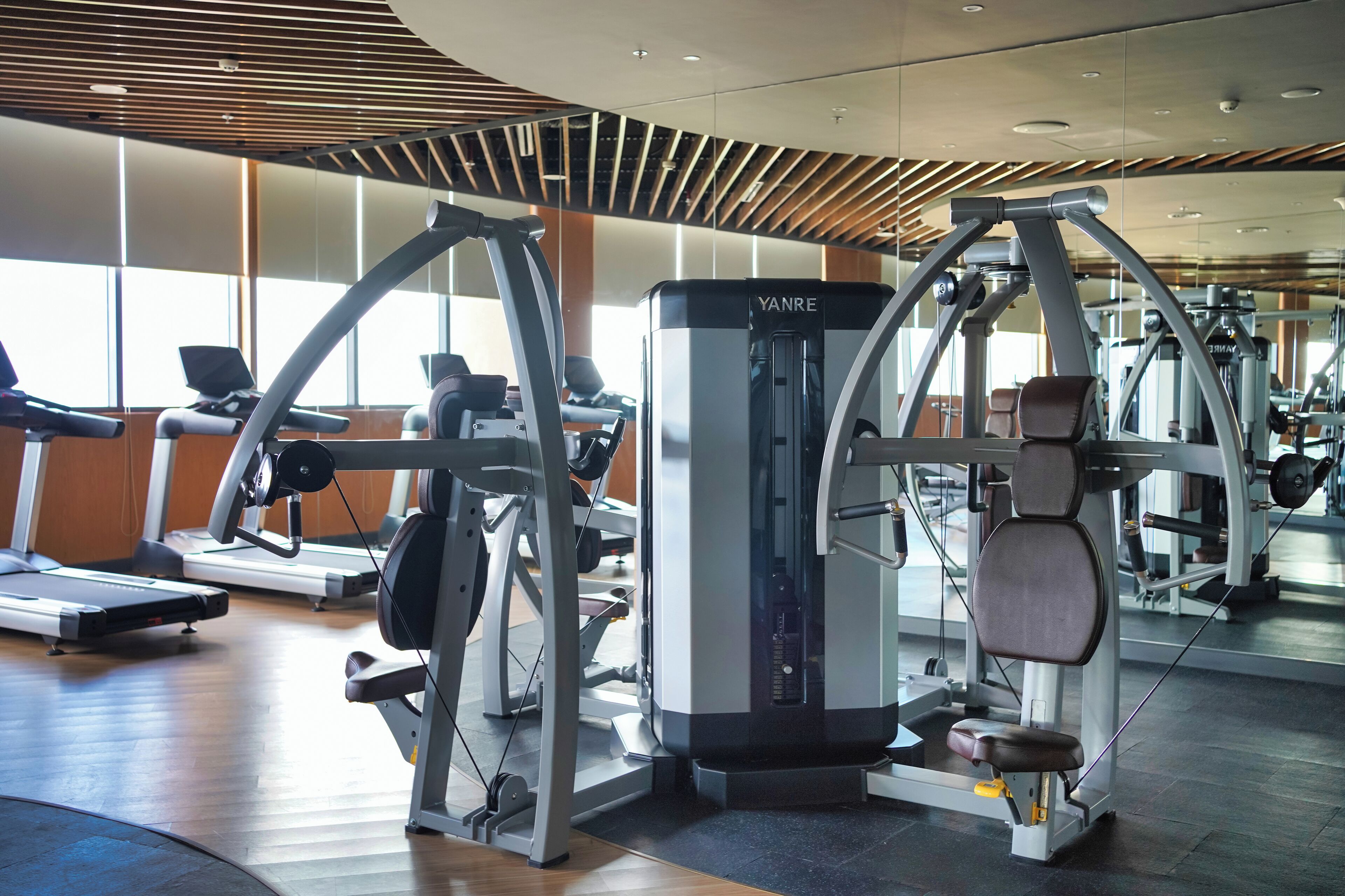 Ein modernes Fitnessstudio mit verschiedenen Trainingsgeräten, darunter Laufbänder und Kraftgeräte.
