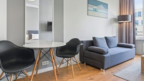 A modern living room with a grey sofa, black chairs, a white table, and a large mirror. - RentPlanet - Apartamenty Sławińska (Warsaw)