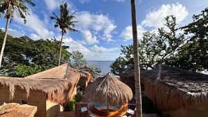 A tropical resort with thatched-roof huts, wooden deck, and a view of the sea. - Nadhibar Resort (Mahinog)