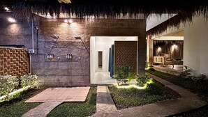A modern building with a thatched roof, a stone facade, and a well-lit entrance. - Nadhibar Resort (Mahinog)
