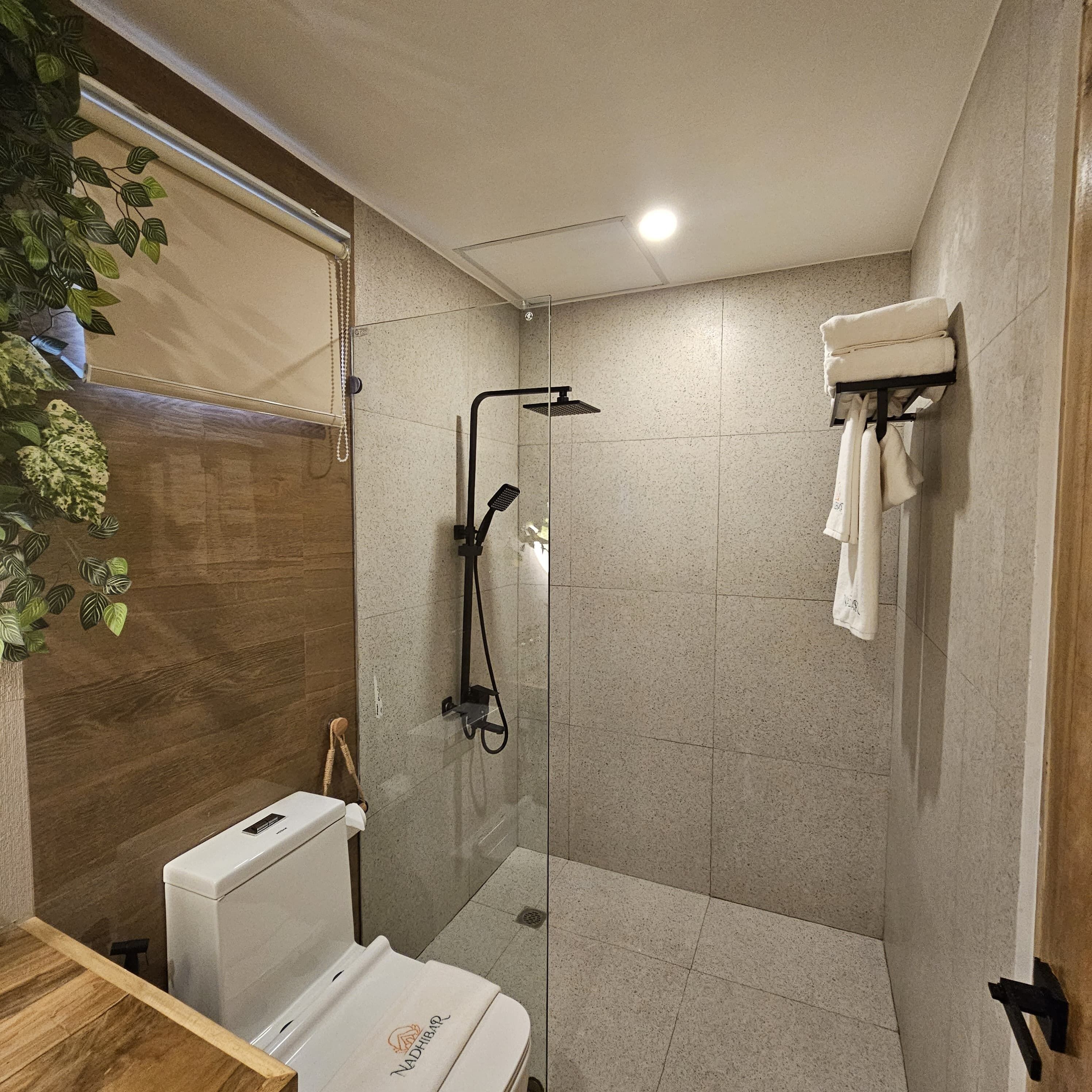 A modern bathroom with a shower, toilet, and a towel rack.