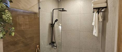 A modern bathroom with a shower, toilet, and a towel rack.