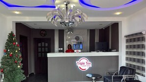 A reception area with a Christmas tree, a clock, and a Triple Tee Luxury Hotel sign. - Triple Tee Luxury Hotel (Lagos)
